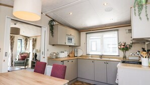 Et lille køkken med spiseplads, med et træbord, stole, en mikrobølgeovn og en vask.
