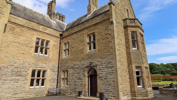 A large stone building with multiple windows, a central entrance, and a small courtyard. - North Wing (Belford)