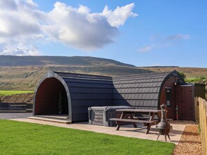 A modern outdoor kitchen with a large barbecue grill, a picnic table, and a covered area. - Lapwing (Carnforth)