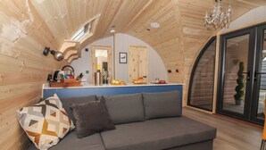 Un intérieur chaleureux en bois, avec un canapé, un petit coin cuisine et une grande fenêtre.