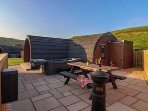 An outdoor patio area with a barbecue setup, picnic table, and seating.