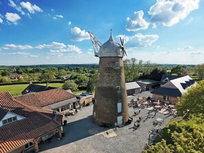 A historic tower with a clock, surrounded by traditional buildings and a courtyard with outdoor seating.