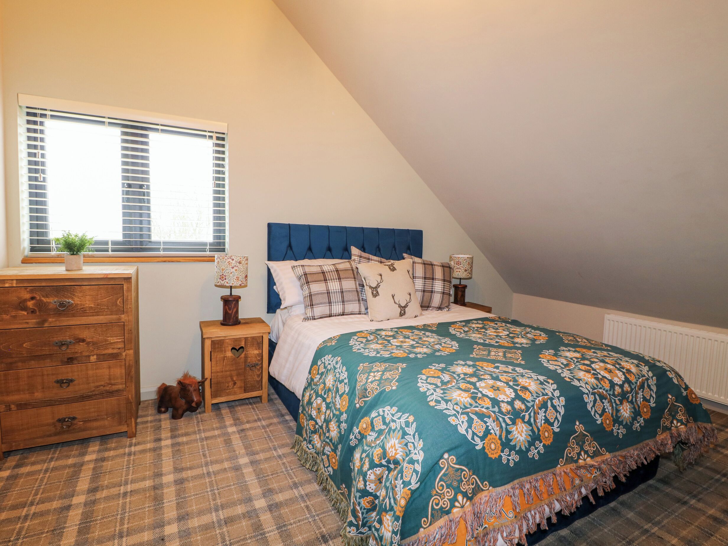 A bedroom with a bed, a dresser, a window, and a radiator.