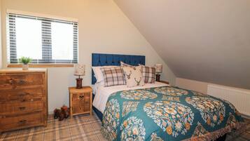 A bedroom with a bed, a dresser, a window, and a radiator.