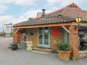 A brick building with a tiled roof, a sign for Brooke Bond Tea, and a sign for Walls Ice Cream.