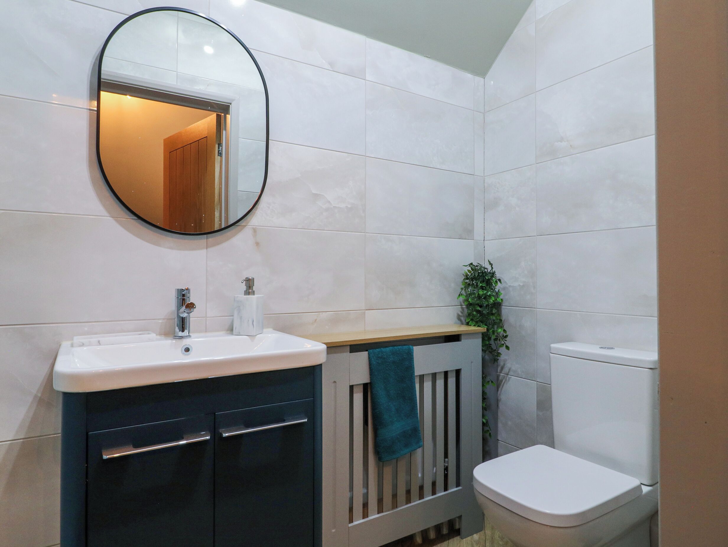 A bathroom with a white sink, a mirror, a toilet, and a towel rack.