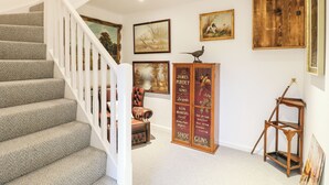A staircase with a white railing, a wooden cabinet with a bird on top, and a framed picture on the wall. - The Oak Room - Windmill Country Retreats (Melton Mowbray)