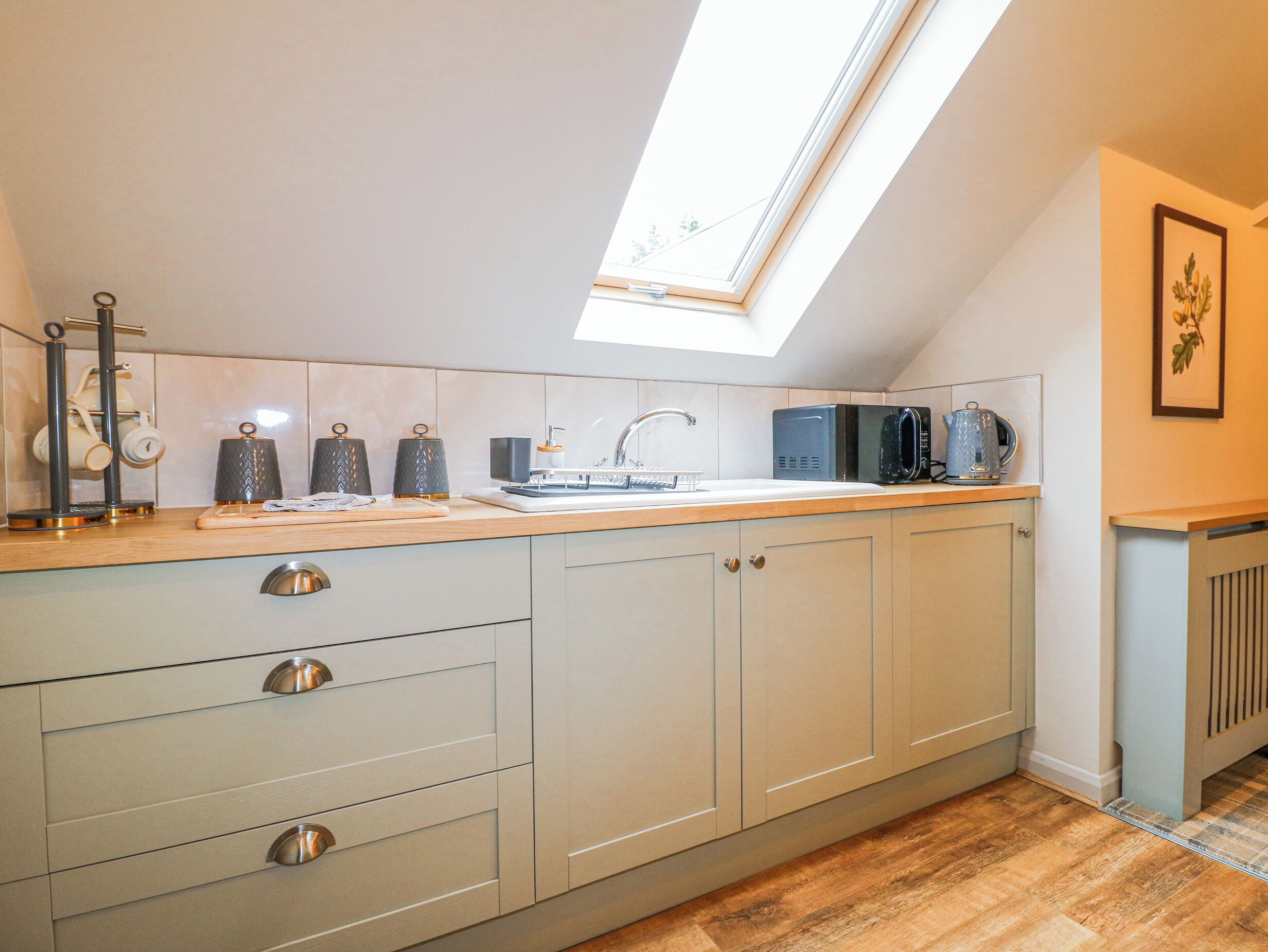 A kitchen with a skylight, a sink, and a coffee maker.