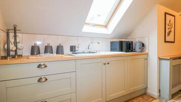 A kitchen with a skylight, a sink, and a coffee maker.
