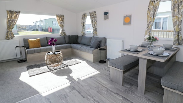 Una sala de estar moderna con un sofá modular, una mesa de comedor con cuencos y platos, y vista a un edificio.