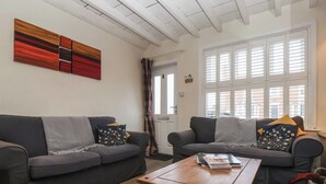 Een gezellige woonkamer met twee grijze banken, een houten salontafel en een vloerkleed met een patroon.