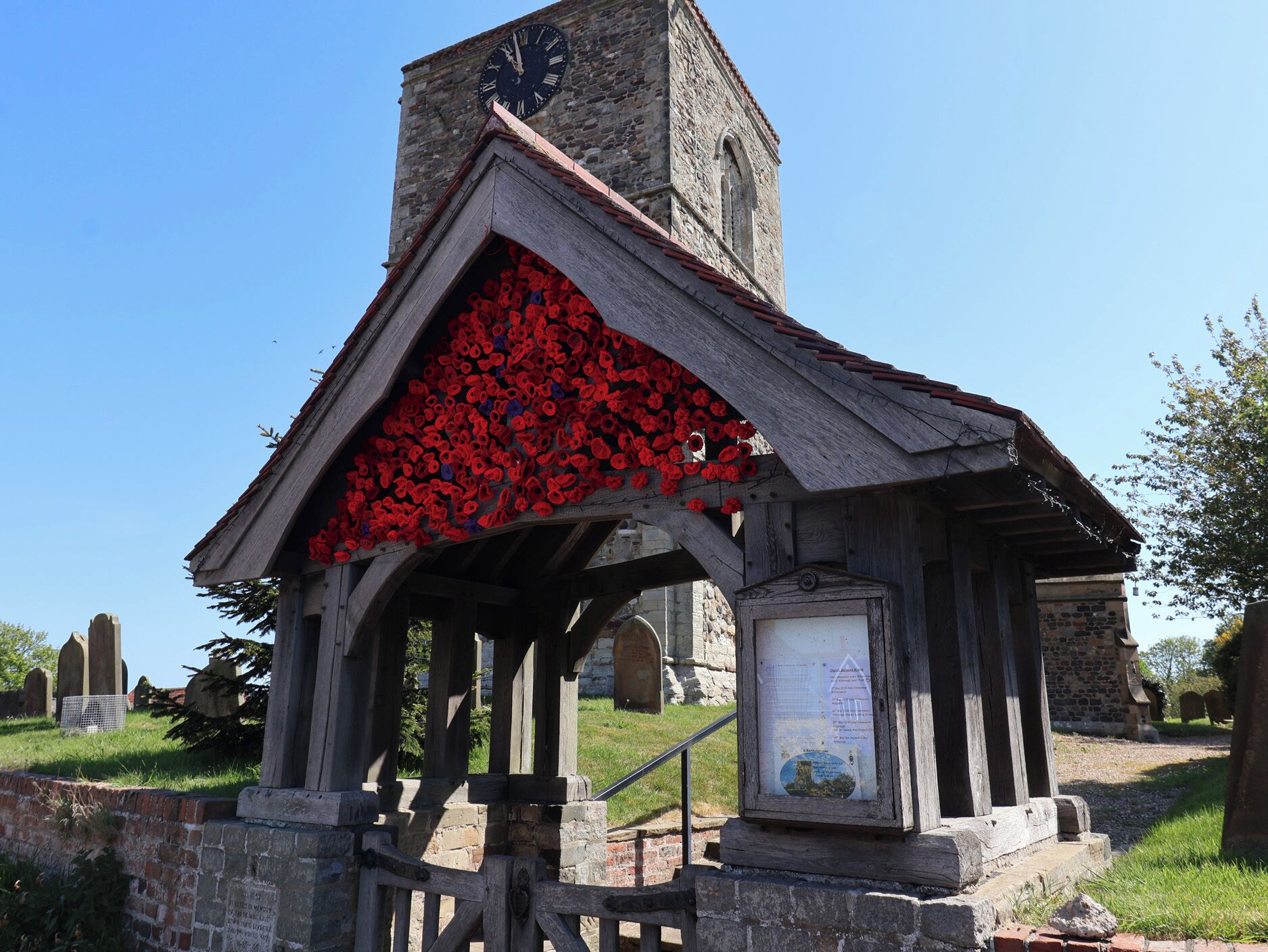 A church with a clock tower and a roof decorated with red flowers.