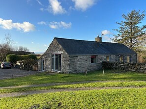A stone cottage with a sloped roof, a small attached shed, and a stone wall. - Hafod Y Llyn (Porthmadog)