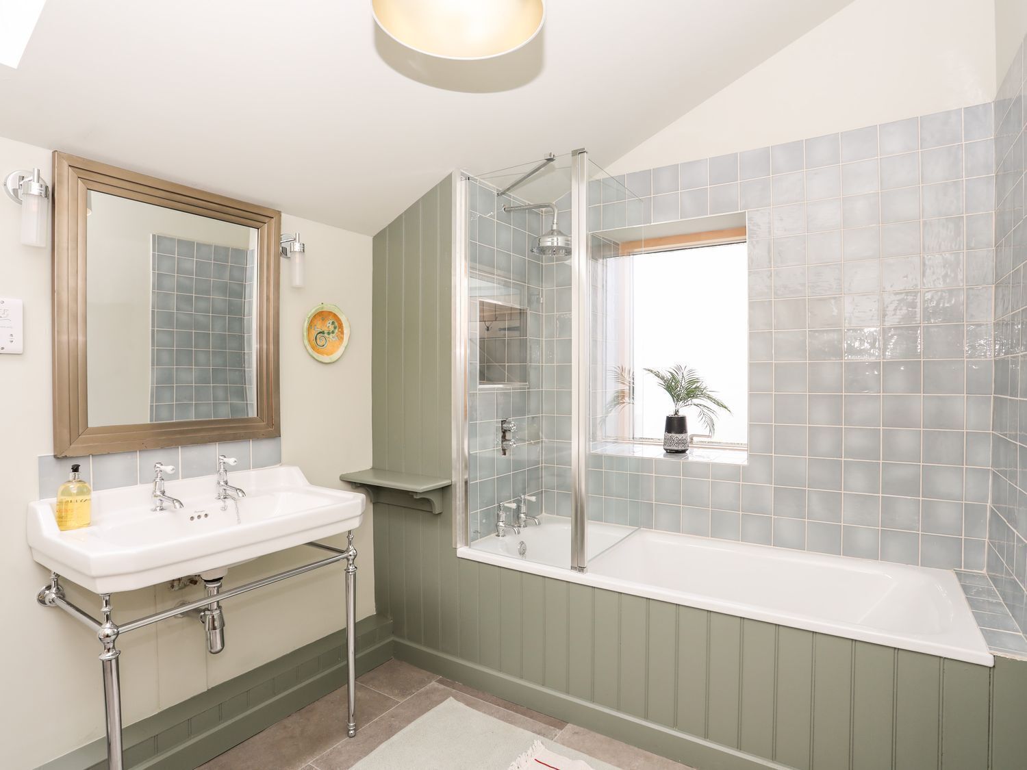 A bathroom with a white sink, a glass-enclosed shower, and a window with a view.