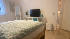 Une chambre à coucher avec un lit, une télévision, une petite plante et un radiateur.