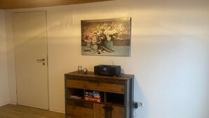 Une pièce avec un meuble en bois, un tableau de fleurs et une porte fermée.