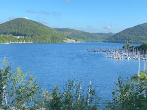 Un lago con un puerto deportivo, rodeado de colinas y vegetación escasa.