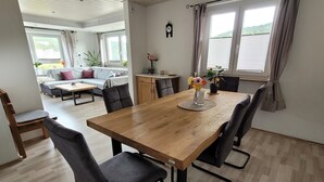 Un comedor con una mesa de madera, sillas negras y un jarrón de flores.