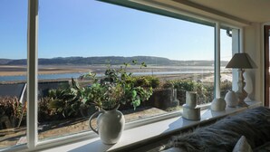 A room with a large window overlooking a river and distant hills. - Swn Y Wylan (Pentraeth)