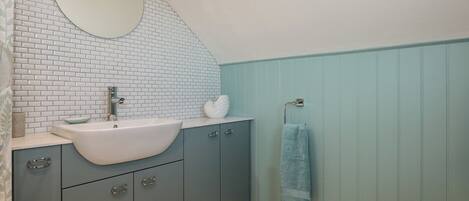 A bathroom with a white sink, a mirror, and a towel rack.
