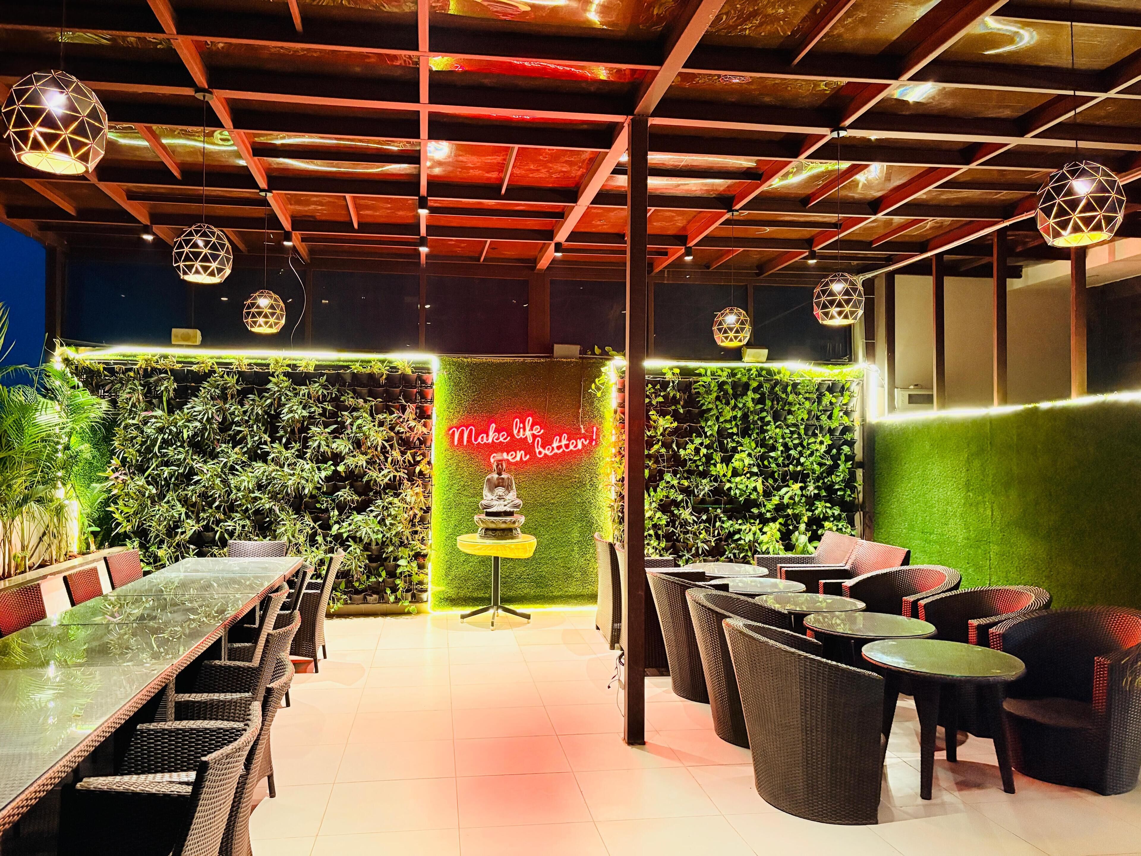 A restaurant with a green wall, a neon sign, and wicker furniture.