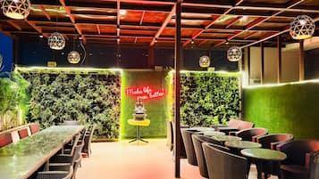 A restaurant with a green wall, a neon sign, and wicker furniture.