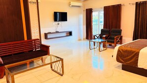 A hotel room with a bed, a sofa, a TV, a chair, and a small table. - Wow Hotels (Tirupur)