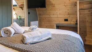 Une chambre dans un chalet en bois, avec un lit, un téléviseur à écran plat fixé au mur et une petite table.