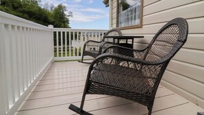 A covered patio with wicker furniture and a white fence. - 26 Manleigh Park (Ilfracombe)