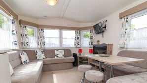 A cozy, well-lit room with a sofa, a small table, and two ottomans. - 26 Manleigh Park (Ilfracombe)