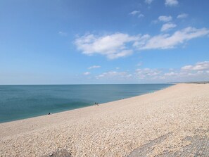 A wide, pebbled beach with a clear sky and calm sea. - 74 Reap Lane (Portland)
