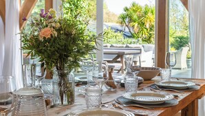 A table set for a meal with glassware, plates, and a vase of flowers. - The Farmhouse at Broad Downs (Kingsbridge)