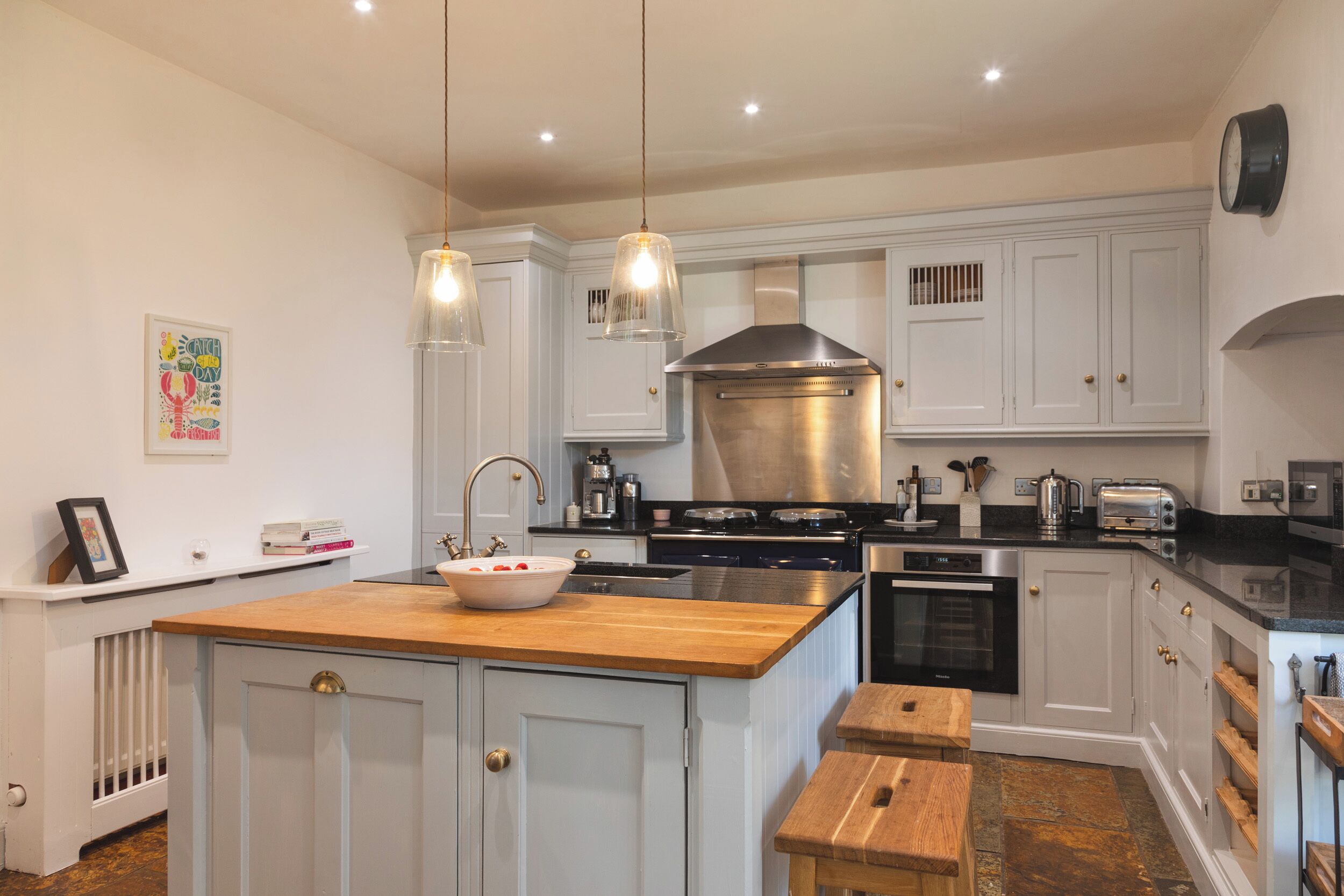 A modern kitchen with white cabinetry, a central island, pendant lighting, and stainless steel appliances.