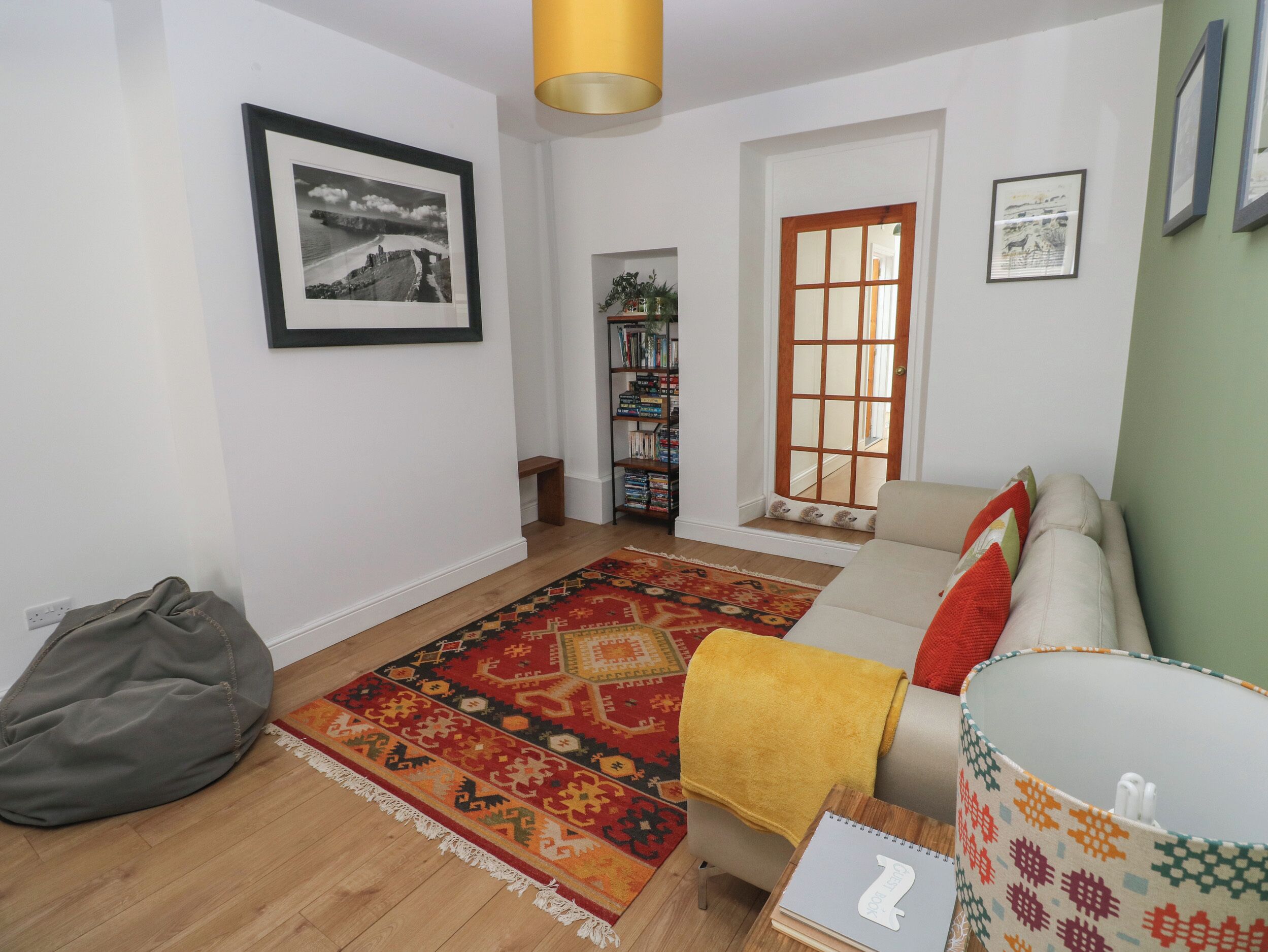 A living room with a sofa, a patterned rug, a bookshelf, and a framed picture on the wall.