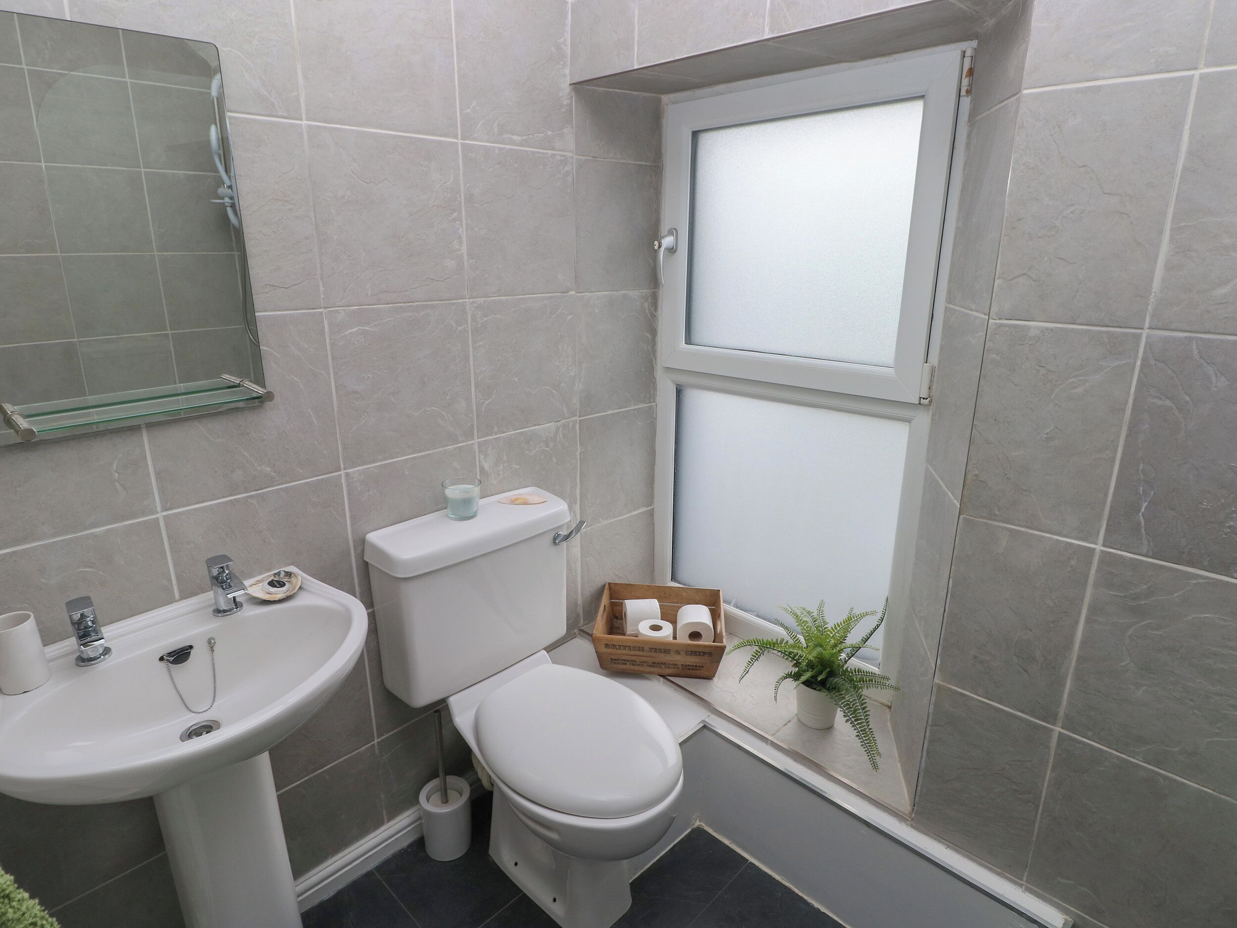 A compact bathroom with a toilet, sink, and window.