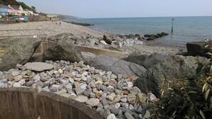 Ein felsiger Strand mit einer Holzpromenade, eine steinige Küste und freie Sicht auf das Meer.