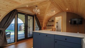 Una cocina moderna con techo de madera, una isla grande y un televisor montado en la pared.