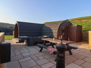 An outdoor patio with a barbecue area, picnic table, and a wooden shed.