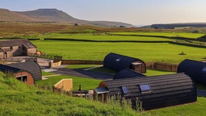 Un paisaje rural con un edificio de piedra y varias construcciones modernas con techos curvos.
