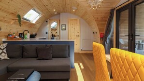 Un interior acogedor de madera, con un sofá, un sillón amarillo y una kitchenette.