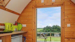 A wooden interior with a kitchen area, a dishwasher, and a view of a picnic table outside. - Hen House @ Penbugle Organic Farm (Liskeard)