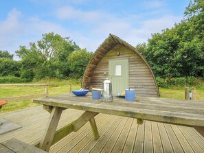 A rustic wooden cabin with a green door, a picnic table with a kettle, bowls, and plates. - Hen House @ Penbugle Organic Farm (Liskeard)