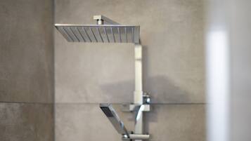 Un cabezal de ducha moderno con diseño rectangular, instalado en una pared con superficie de azulejos lisos.