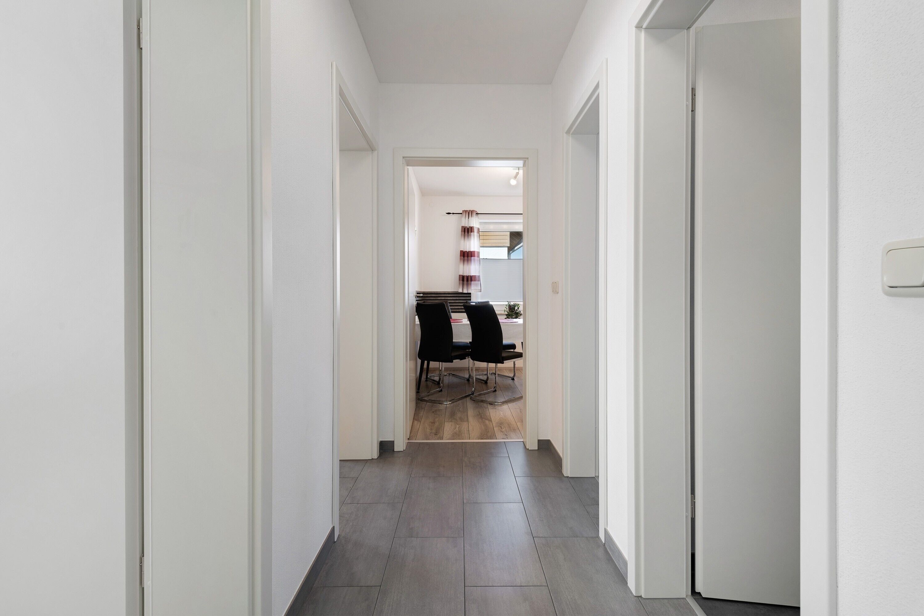 Un couloir étroit qui se termine par un coin repas, avec une table et des chaises.