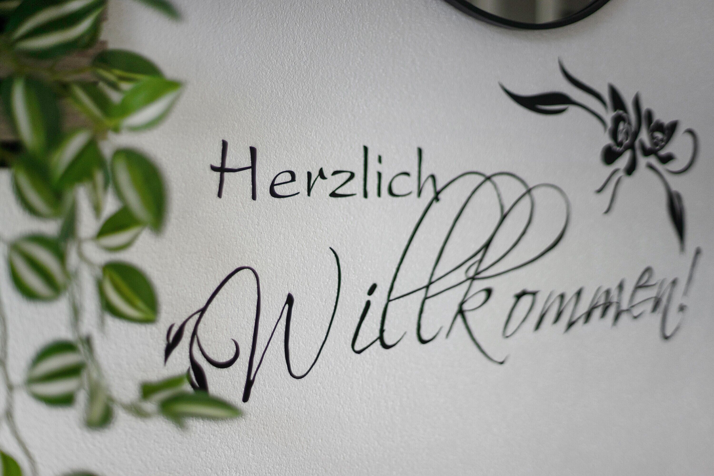 Una pared con la inscripción 'Herzlich Willkommen!' y un diseño floral.