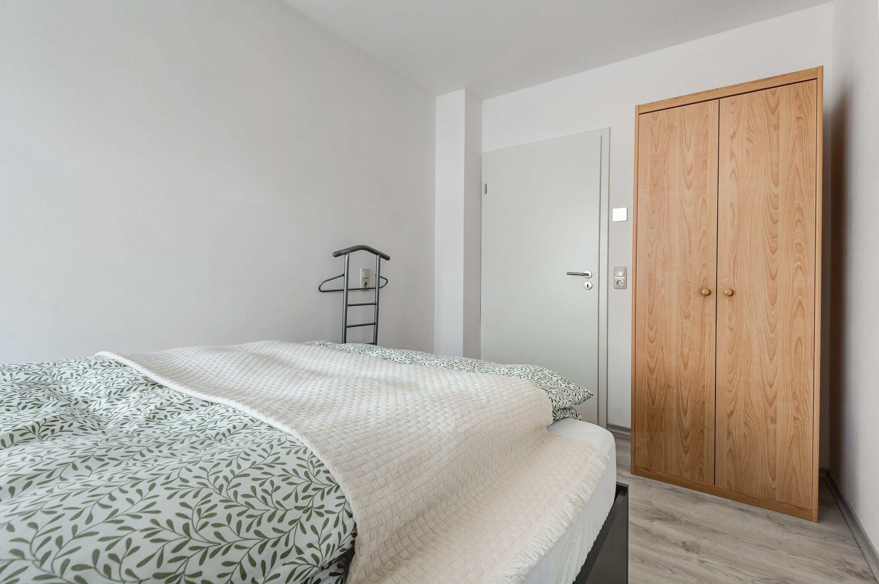 A bedroom with a bed, a wardrobe, and a ladder against the wall.