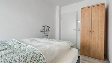 A bedroom with a bed, a wardrobe, and a ladder against the wall.