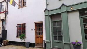 Een wit gebouw met een groene deur en ramen. Aan de linkerzijde hangt een vlag.