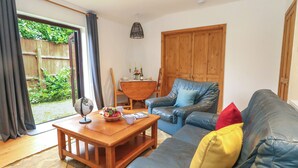 Ein Wohnzimmer mit Ledersofa, Couchtisch aus Holz und einem Esstisch mit Stühlen.