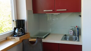 A compact kitchenette with a coffee maker, a bottle of dish soap, and a small sink.